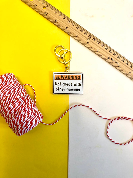 birds eye view of a keychain that reads "warning not great with other humans"